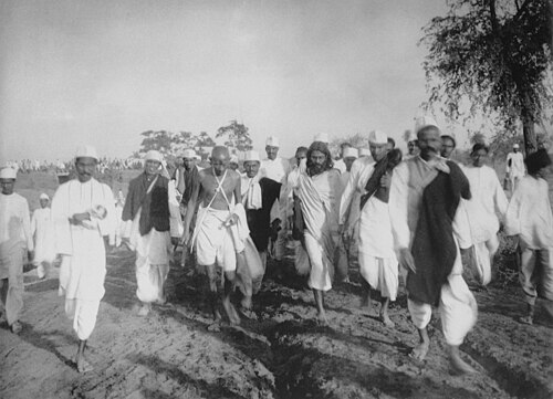 Black-and-white photograph of Mahatma Gandhi walking with followers during the 1930 Salt March