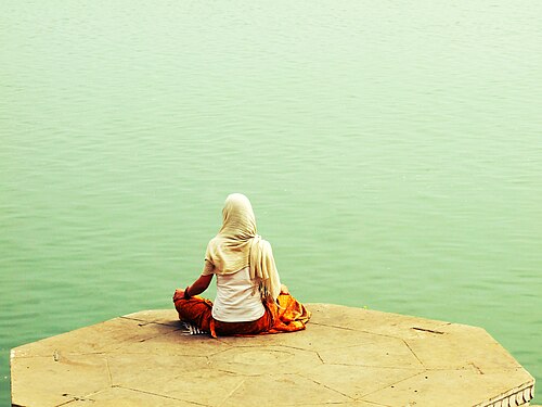 A Hindu sitting in cross-legged meditation by the river Ganges
